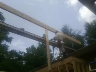 Carpenter setting a ridge beam over a new addition frame — Ice Dam Removal by Roofing Brothers in Deposit