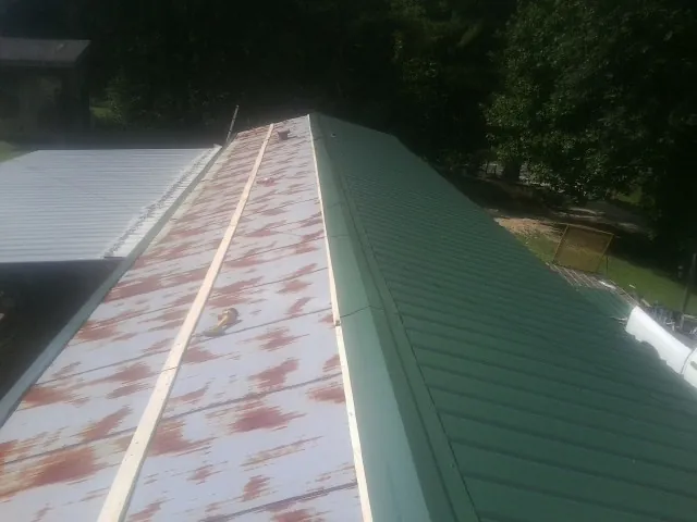 Old rusted panels beside newly installed green metal roofing — Wind Damage Roof Repair by Roofing Brothers in Deposit