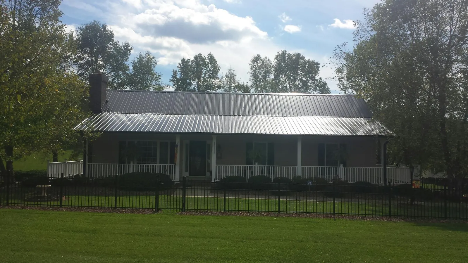 Gray metal roof on a brick ranch with a full width front porch — Gutter Guard Installation work by our crew in Deposit