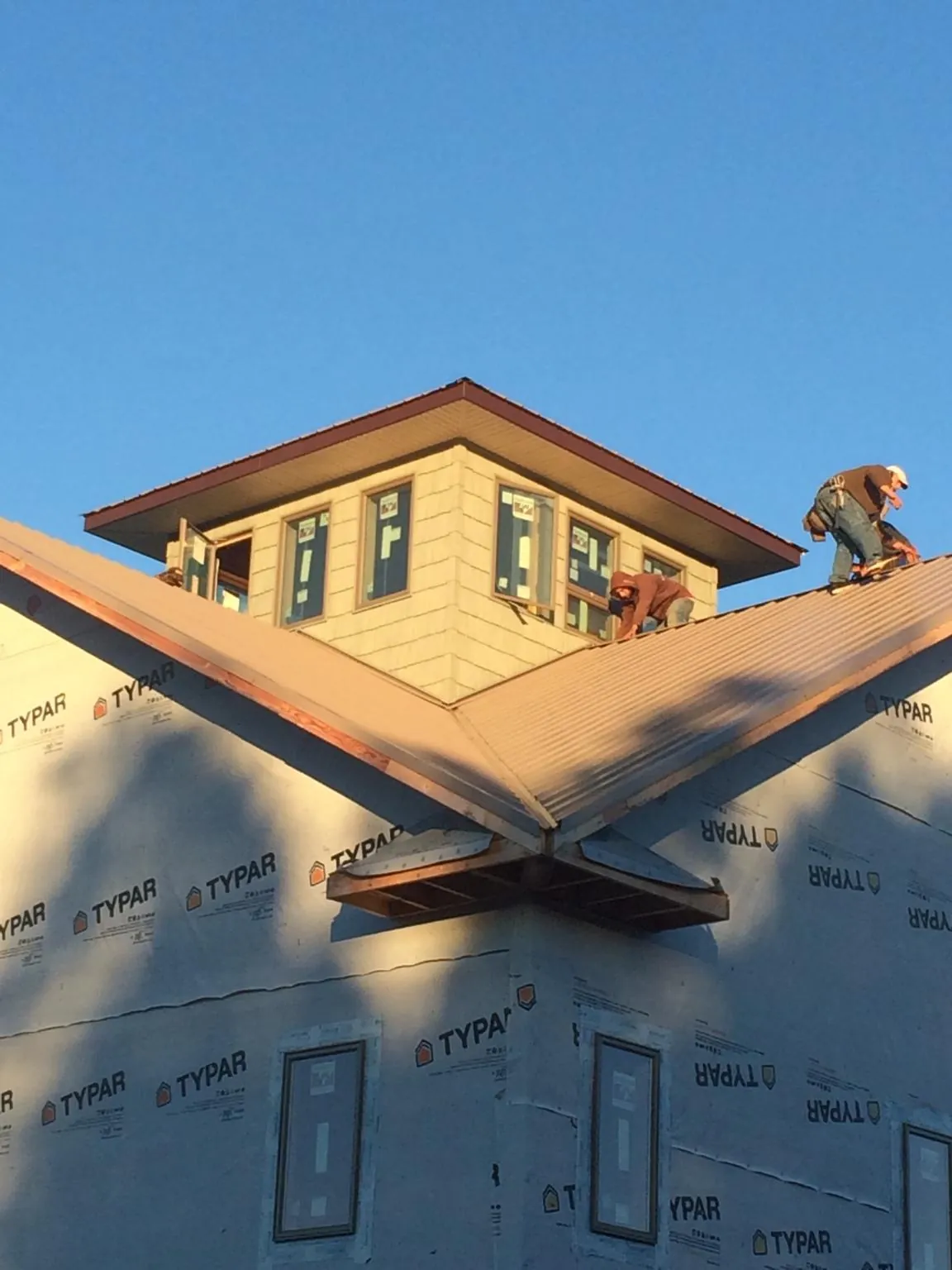 Roofers working around a rooftop cupola on a new metal roof at sunset — Roof Waterproofing in Deposit by Roofing Brothers